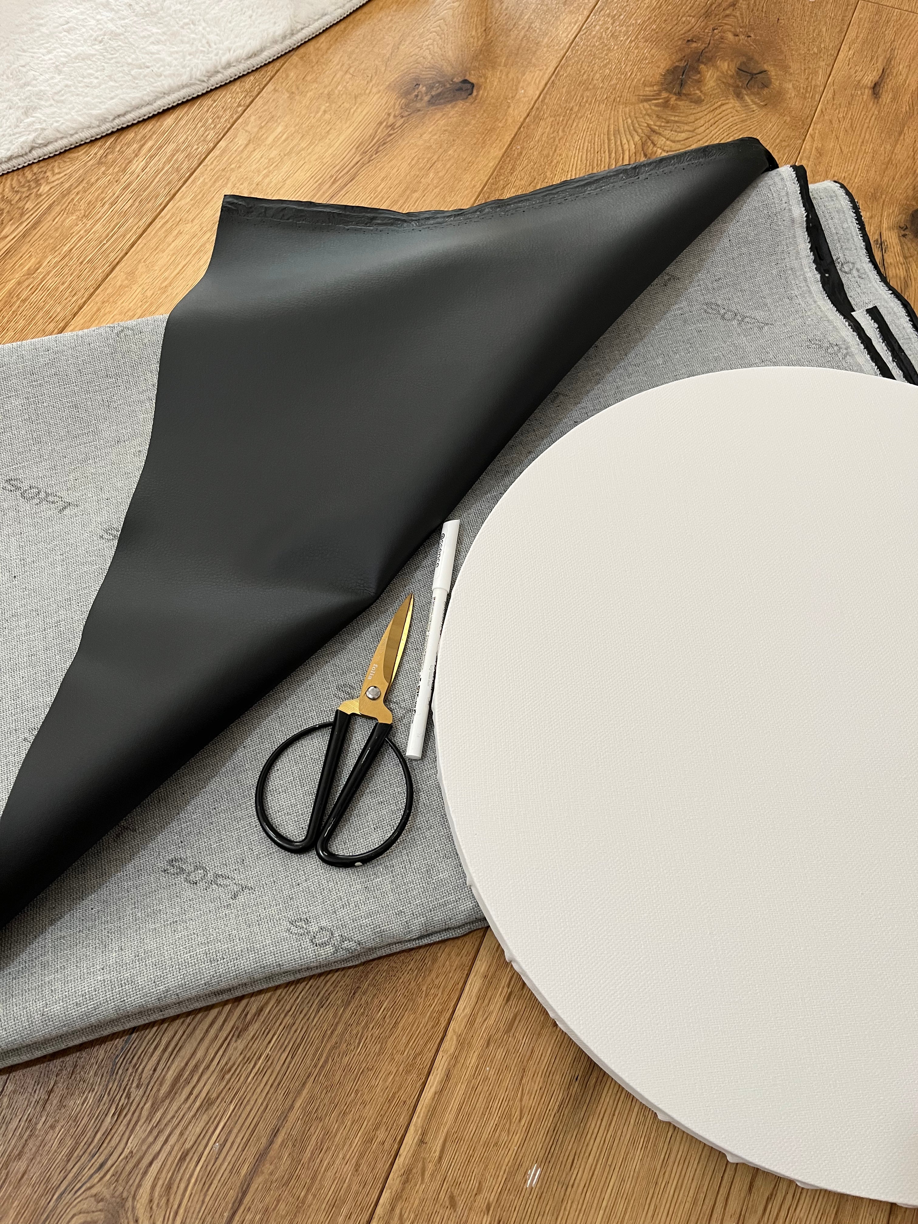 Atelier Detailfoto Kunstleder, gold schwarze Schere, kleine runde Leinwand auf Parkettboden. Nadine Elsner modern Wabi Sabi Art 