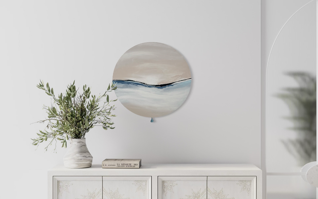 Das Kunstwerk "calm breath". Moderne Wabi Sabi Kunst mit daoistischer Seele von Nadine Elsner. 60cm im Durchmesser. Weiche nude und kühlende blau Töne mit weichem Kunstlederstreifen in der Mitte. Sanfter Abschluss mit einer kleinen blauen Quaste. Das Bild bringt Wärme und Klarheit in ein einen sehr schönen hellen Raum.