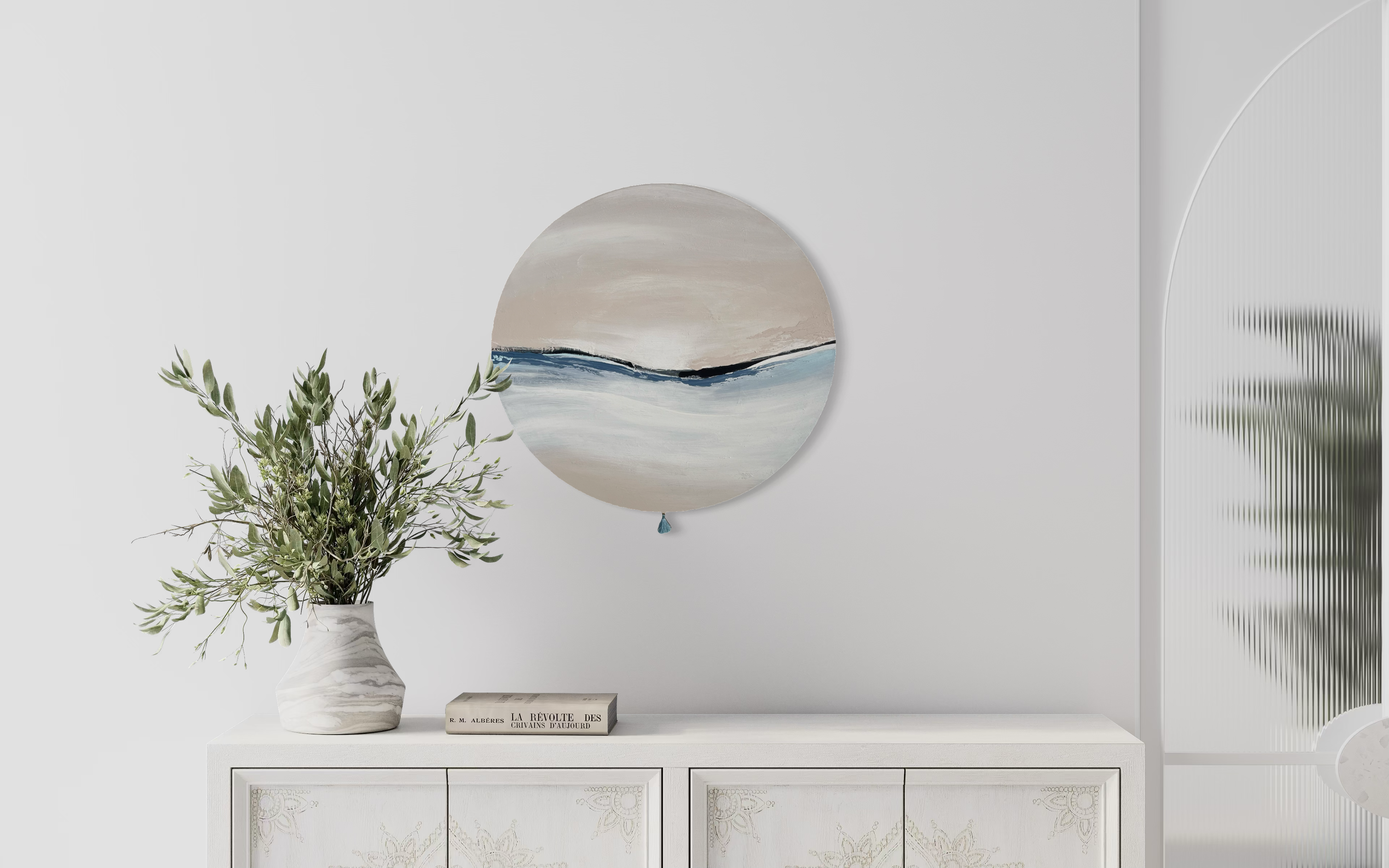 Das Kunstwerk "calm breath". Moderne Wabi Sabi Kunst mit daoistischer Seele von Nadine Elsner. 60cm im Durchmesser. Weiche nude und kühlende blau Töne mit weichem Kunstlederstreifen in der Mitte. Sanfter Abschluss mit einer kleinen blauen Quaste. Das Bild bringt Wärme und Klarheit in ein einen sehr schönen hellen Raum.