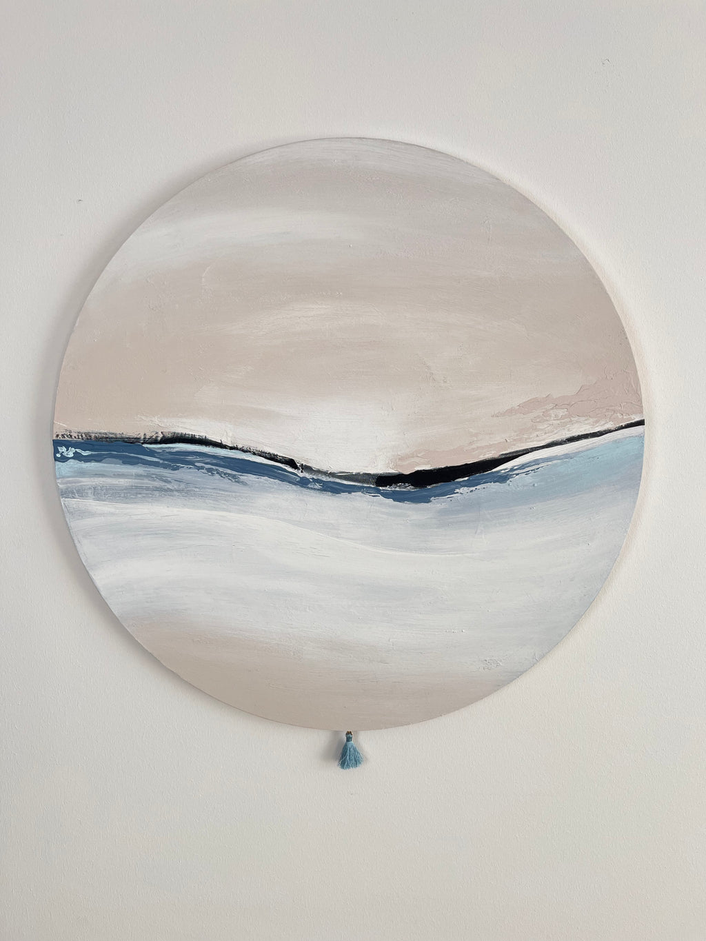 Das Kunstwerk "Calm Breath". Das Werk ist insgesamt in einem sehr zarten weichen nude Ton gehalten. Im unterem Teil beginnt das Werk sehr hell in weiß und verläuft nach unten wieder in den nude Ton. Durch die Mitte zeiht sich ein zarter Streifen aus Kunstleder. Oben begleitet ihn von rechts nach links ein warmer Farbauftrag im nude Ton. Darunter ein kühlerer in Blautönen. Den sanften Abschluss bildet eine hellblaue kleine Quaste.