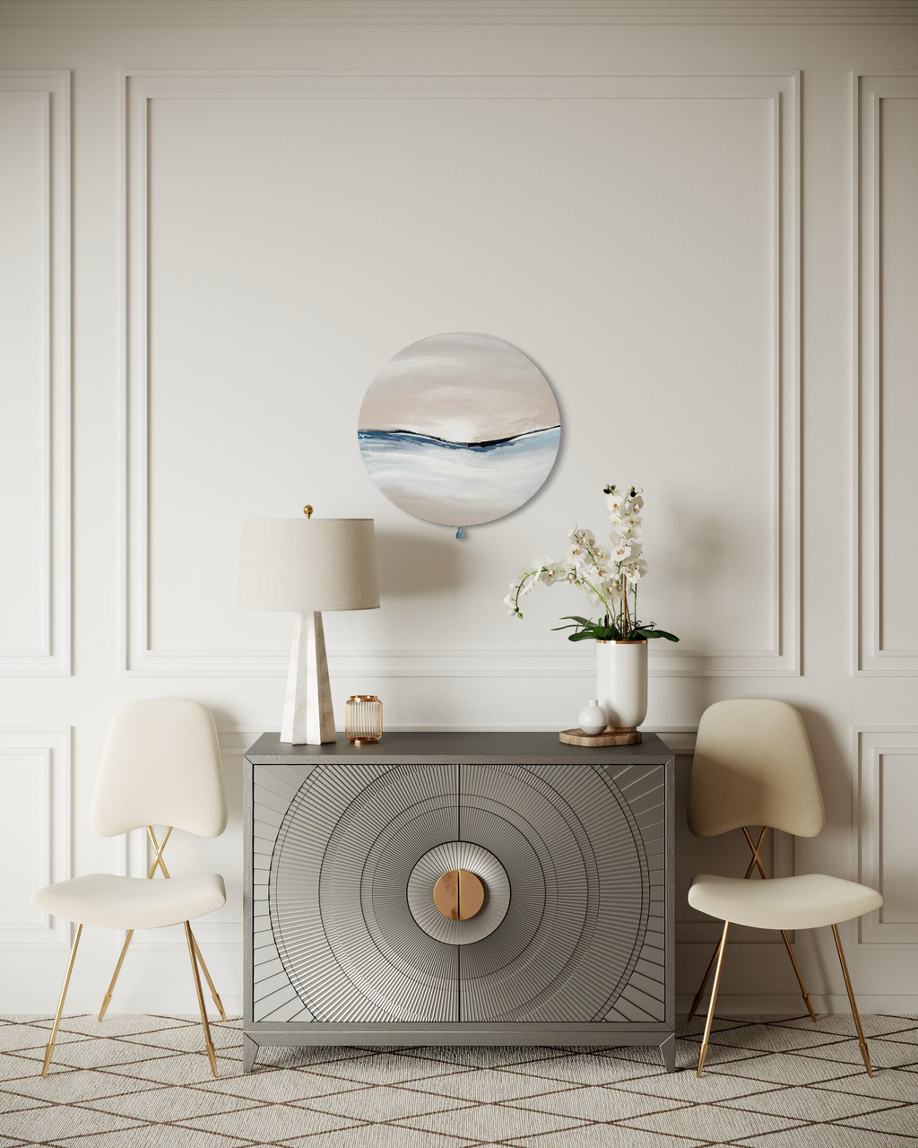 Das Kunstwerk "calm breath". Moderne Wabi Sabi Kunst mit daoistischer Seele von Nadine Elsner. 60cm im Durchmesser. Weiche nude und kühlende blau Töne mit weichem Kunstlederstreifen. Sanfter Abschluss mit einer kleinen blauen Quaste. Das Bild ergänzt einen zart beigen Raum, hängt über einer mit Mustern verzierten hellgrauen Kommode. Überall sind Goldelemente an den Möbeln. Alles Wirt sehr harmonisch. Beim Anschauen im Raum des Werkes versunken in warmer Geborgenheit und kühlem Atem.