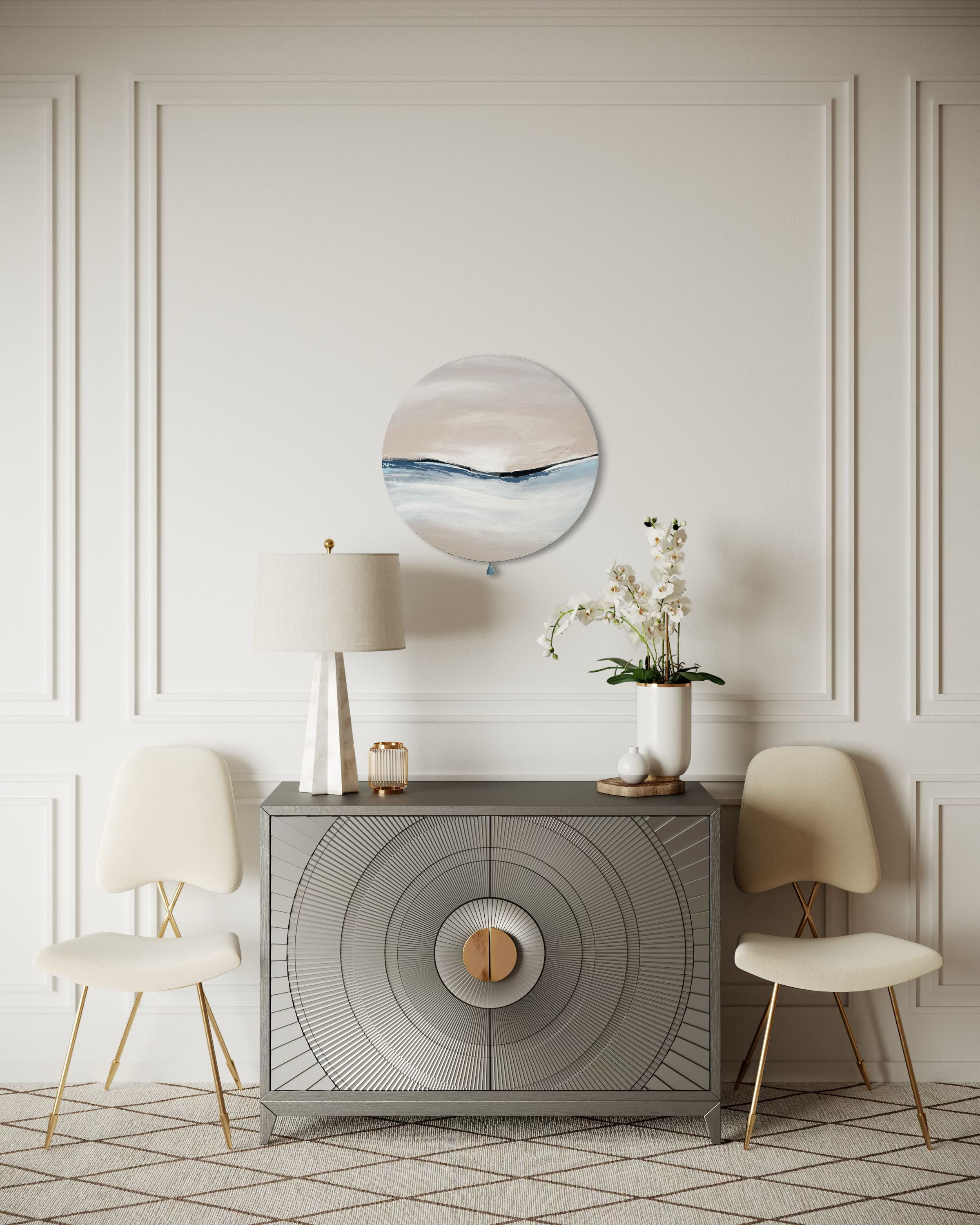 Das Kunstwerk "calm breath". Moderne Wabi Sabi Kunst mit daoistischer Seele von Nadine Elsner. 60cm im Durchmesser. Weiche nude und kühlende blau Töne mit weichem Kunstlederstreifen. Sanfter Abschluss mit einer kleinen blauen Quaste. Das Bild ergänzt einen zart beigen Raum, hängt über einer mit Mustern verzierten hellgrauen Kommode. Überall sind Goldelemente an den Möbeln. Alles Wirt sehr harmonisch. Beim Anschauen im Raum des Werkes versunken in warmer Geborgenheit und kühlem Atem.