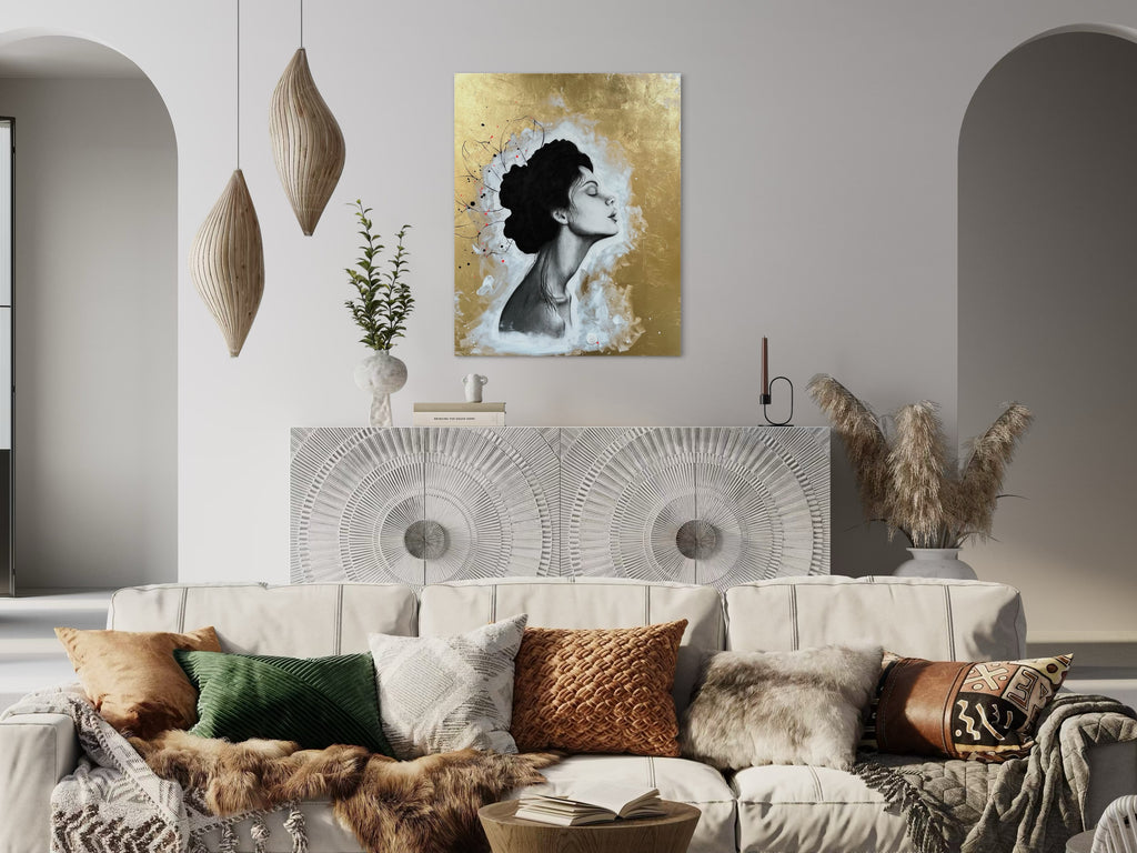 Das Kunstwerk hängt über einer hellgrauen Kommode. Diese ist mit einer Naturverzierung gestaltet. Vor der Kommode steht eine hellbeige Couch mit naturfarbenen Kissen. 